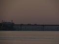 Dawn cityscape with a black contour of the morning bridge against the sky and the river.