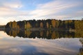 Dawn in the forest near the lake. The forest is reflected in the water. Autumn Early morning. Russia Royalty Free Stock Photo