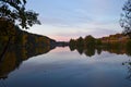 Dawn in the forest near the lake. The forest is reflected in the water. Autumn Early morning. Russia Royalty Free Stock Photo