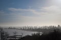 Misty harbor view with silhouette of cranes, ships, and industry skyline. Dawn light softens seascape, outlines of