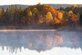 Dawn mist on the lake with forest in autumn colors Royalty Free Stock Photo