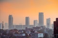 dawn shot of skyscrapers houses shot partially hidden in fog with the warm orange of dusk showing the start of a new day