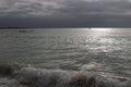 Dawn with stormy sky over the silver ocean. Lone fisherman boat in the water.