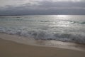 Dawn with stormy sky over the silver ocean. Lone fisherman boat in the water.