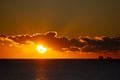 Dawn sun go behind cloud over sea horizon during dawn. Sunbeams, sun rays Royalty Free Stock Photo