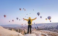At dawn a tourist with a backpack on the background of soaring hot air balloons in Cappadocia, Turkey, concept achievement, team,