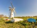 Boats on a grassy bank and a windmill in the background Royalty Free Stock Photo
