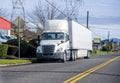 Day cab big rig semi truck with dry van semi trailer parked on the city street road waiting for load Royalty Free Stock Photo