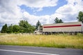 Day cab big rig semi truck with roof spoiler transporting commercial cargo moving on the hill road with brush grass and cloudy sky