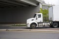 Day cab big rig white semi truck with dry van semi trailer running on the road under bridge Royalty Free Stock Photo