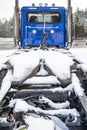Day cab blue big rig semi truck tractor with covered by snow frame and fifth wheel hitch saddle standing on the industrial Royalty Free Stock Photo