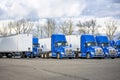 Day cab bright blue big rig semi trucks and dry van semi trailers standing in row on the industrial parking lot waiting for the Royalty Free Stock Photo