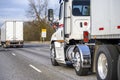 Day cab white big rig semi truck with chrome fenders transporting cargo in dry van semi trailer running in convoy behind another Royalty Free Stock Photo