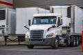 Day cab white big rig semi truck tractor with refrigerator semi trailer unloading delivered cargo parking in store dock gate Royalty Free Stock Photo