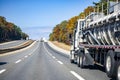 Big rig day cab white semi truck transporting cargo in tank semi trailer for chemicals and other liquids running on the wide Royalty Free Stock Photo