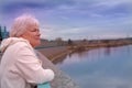 Day dreaming senior woman outdoors. Contented senior woman looking thoughtful during walking countryside