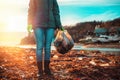 Day of Earth. A female volunteer stands on a muddy beach with a bag of garbage. Sunset