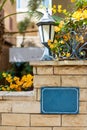 Day shot of shabby brick fence with signboard and street lantern with blooming flowers Royalty Free Stock Photo