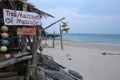 A day shot of a small wooden and bamboo shack on a white sand beach offering thai and oil massage services. The hut is on a small