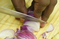 Closeup view of onion cutting with knife,Male finger and cutting board in the background Royalty Free Stock Photo