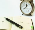 Day timer organizer with a pen and a mechanical alarm clock, time management and activity planning concept