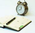 Day timer organizer with a pen and a mechanical alarm clock, time management and activity planning concept