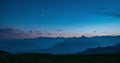 Day to night time lapse from high up on the Alps. Colorful sunset over mountain peaks and fog in the valleys below, moving clouds,