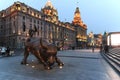 Day view of the Bund of Shanghai and the bronze bull and some tourists passing by