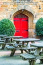 Day view of empty typical pub garden with tables and red antique doors in England Royalty Free Stock Photo