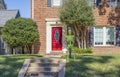 Dayglo Halloween skeleton attached to lamp post outside upscale brick house with beautiful bright red front door Royalty Free Stock Photo