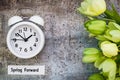 Daylight Savings Time Spring Forward concept top down view with white clock and green tulips Royalty Free Stock Photo