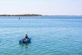 Daylight view to a fisherman in blue boat preparing fishing rod Royalty Free Stock Photo