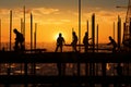 Daylight wanes as construction workers continue their tasks, framed by the setting sun Royalty Free Stock Photo