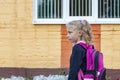 Daylight. a young girl with old hair and a backpack on her shoulders goes to school Royalty Free Stock Photo
