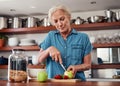 These days, she only eats healthy. an attractive senior woman chopping up apples and other fruit while preparing Royalty Free Stock Photo