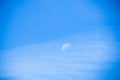 Daytime blue sky with a few light clouds and a large half moon in center Royalty Free Stock Photo