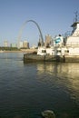 Daytime view of tug boat pushing barge down Mississippi River in front of Gateway Arch and skyline of St. Louis, Missouri as seen