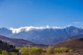 Daytime wide angle shot of Beautiful landscape of snow capped mountains and bushes and a village in the valley. Atlas, Morocco