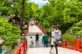 Tourists and local japanese people walk across the beautiful red bridge leading to the famous Tenmangu Shrine in Dazaifu, Japan Royalty Free Stock Photo