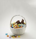 A white basket with full of multicolor candies, Jelly Beans, bunny chocolate, Easter holiday food, generative AI Royalty Free Stock Photo