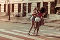 Dazzling lady hugging with her girlfriend while walking the streets