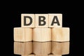 DBA text assembled from wooden cubes on a black background