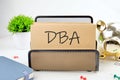 DBA text on paper next to piggy bank, notepad, flower on a white background