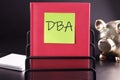 DBA text on a yellow sticker pasted on an upright diary on a black background Royalty Free Stock Photo
