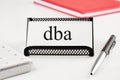 DBA the word on the business card standing on a stand next to a notepad, calculator and pen