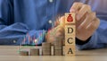 DCA word on a wooden cube and man hands holding money icon on wooden cude.Saving Coins, Saving Money.Dollar Cost Averaging Royalty Free Stock Photo