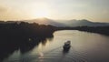 Boat sailing towards Sunset in front of Mountain Ridge. Drone Shot. Royalty Free Stock Photo