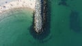 A top-down aerial drone shot of a rock barrier in Bray Beach, Ireland, on a sunny day with emerald waters and white sands Royalty Free Stock Photo