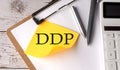 DDP word on a yellow sticky with calculator, pen and clipboard Royalty Free Stock Photo