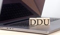 DDU word on wooden block on laptop, business concept